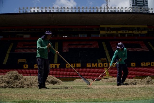 Funcionários rastelam grama no gramado da Ilha do Retiro